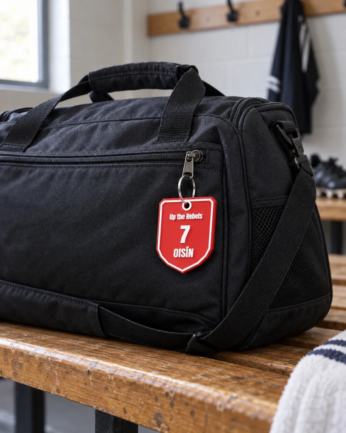 Personalised Cork GAA bag tag with OISÍN and number 7 hanging from a dark sports kit bag in a changing room
